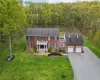 View of front of property with a garage, a front lawn, and a porch