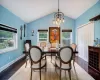 Dining space featuring dark hardwood / wood-style flooring, an inviting chandelier, a healthy amount of sunlight, and lofted ceiling