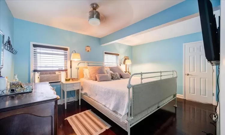 Bedroom with ceiling fan, cooling unit, and dark wood-type flooring