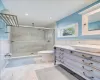 Bathroom featuring tile patterned flooring, a shower with shower door, toilet, vanity, and tile walls