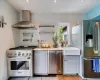 Kitchen with tile patterned flooring, stainless steel appliances, sink, and wall chimney range hood