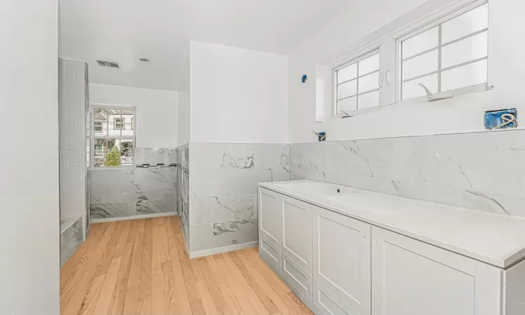 Bathroom with tile walls, shower with separate bathtub, and hardwood / wood-style floors