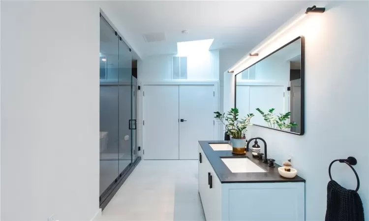 Bathroom featuring a shower with door, wood-type flooring, and double vanity