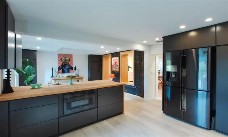 Kitchen featuring oven, light hardwood / wood-style flooring, butcher block counters, and stainless steel refrigerator with ice dispenser