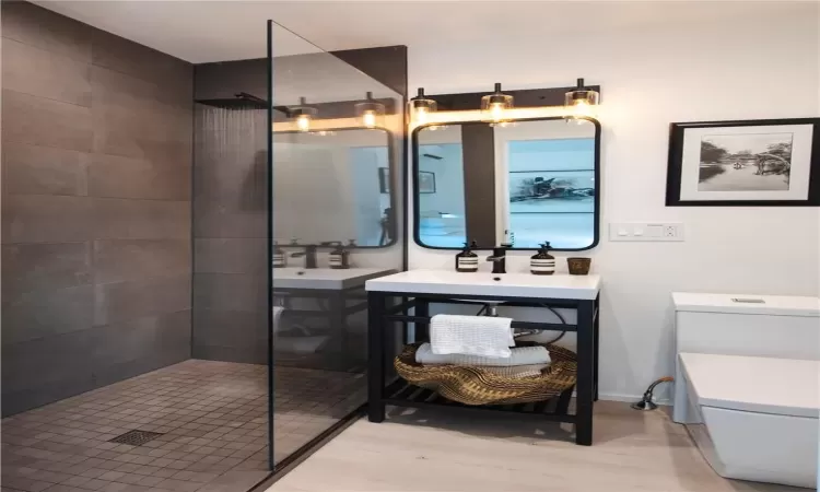 Bathroom featuring vanity, a tile shower, and hardwood / wood-style flooring