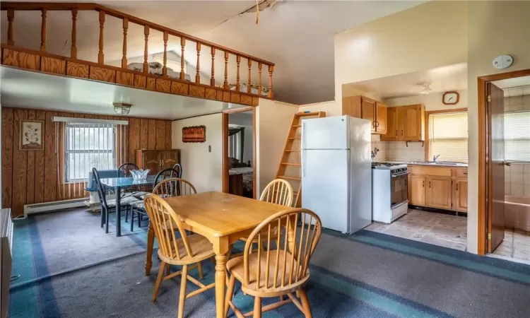 Dining area with a high ceiling, wood walls, sink, and a baseboard heating unit