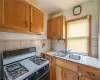 Kitchen featuring backsplash, tile counters, white gas stove, and sink