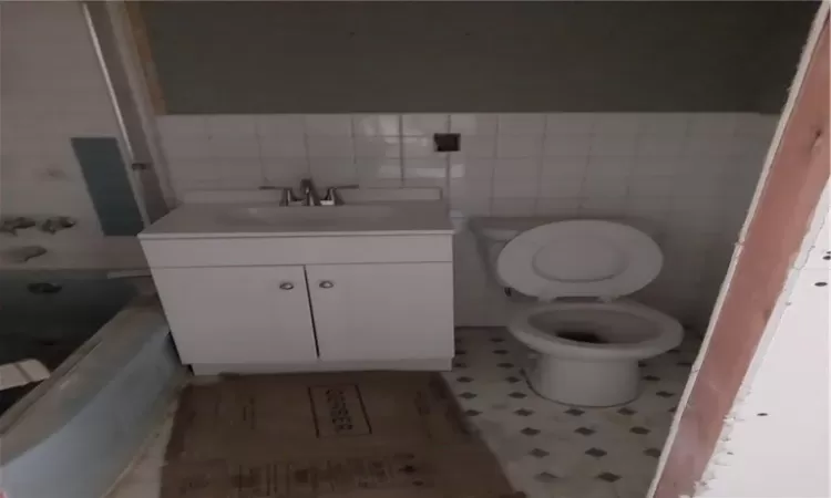 Bathroom with vanity, toilet, backsplash, and tile walls