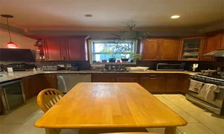 Kitchen with tasteful backsplash, light tile patterned floors, beverage cooler, stainless steel appliances, and sink