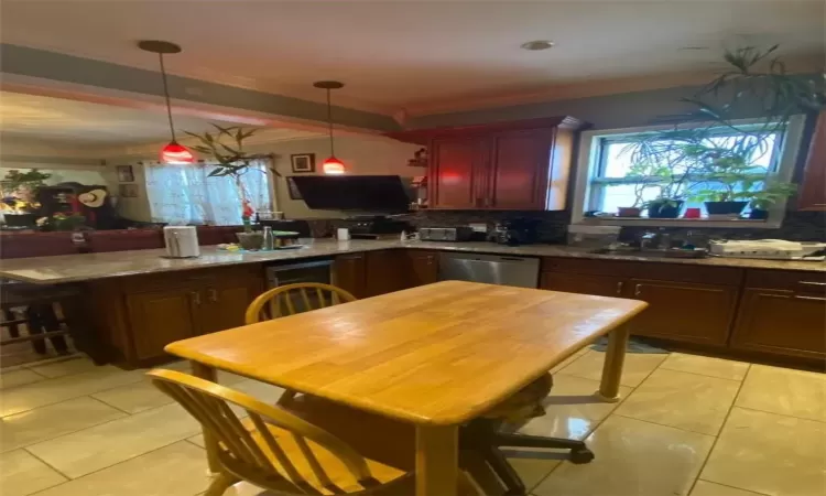 Kitchen featuring stainless steel dishwasher, light tile patterned floors, decorative backsplash, crown molding, and kitchen peninsula