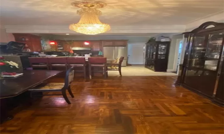 Dining space with crown molding, a notable chandelier, and parquet flooring