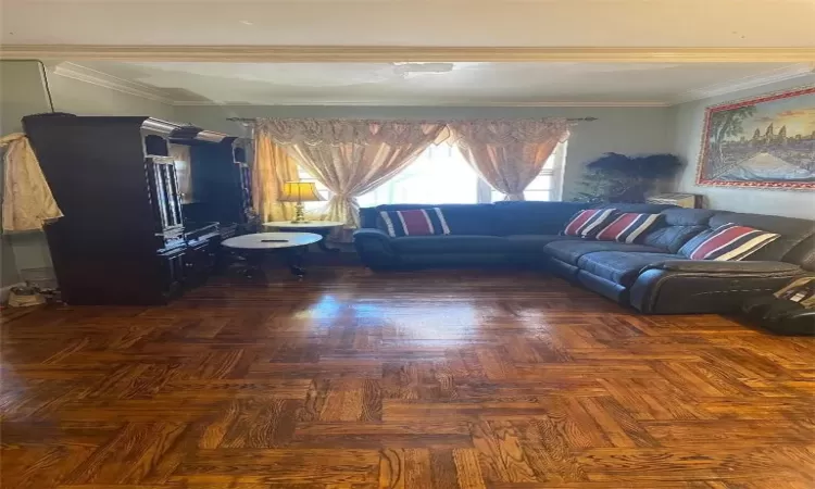 Unfurnished living room featuring ornamental molding and dark parquet floors