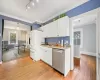 Kitchen featuring hanging light fixtures, light hardwood / wood-style flooring, stainless steel dishwasher, and white cabinets