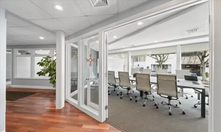 Office space with a drop ceiling, dark wood-type flooring, and lofted ceiling