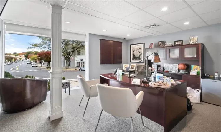 Carpeted office space with a paneled ceiling and decorative columns