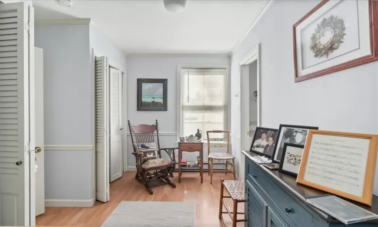 Living area with light hardwood / wood-style floors and ornamental molding