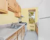 Kitchen with white appliances, sink, radiator heating unit, extractor fan, and light tile patterned floors