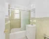 Bathroom featuring vanity, tile walls, and bath / shower combo with glass door