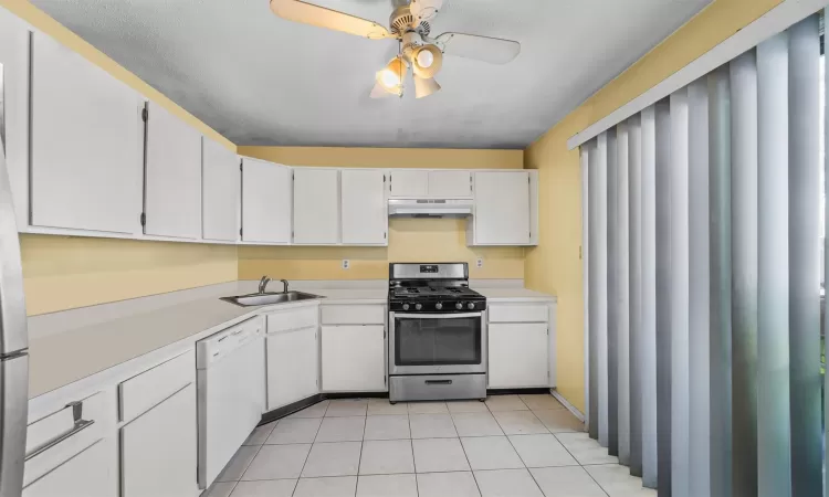 Kitchen featuring white dishwasher, stainless steel gas range oven, white cabinetry, and sink