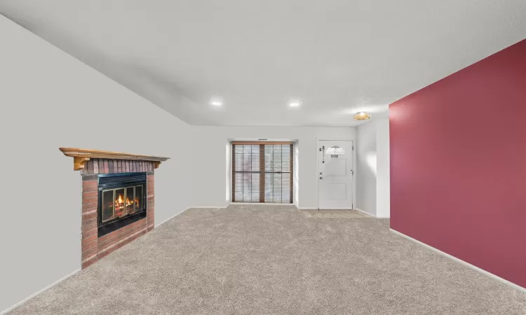 Unfurnished living room featuring carpet floors and a brick fireplace