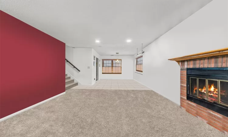 Unfurnished living room featuring light carpet and a fireplace