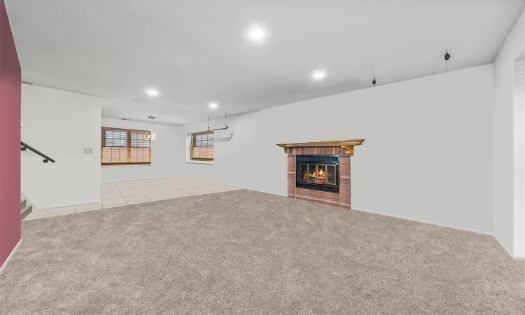 Unfurnished living room featuring light colored carpet and a brick fireplace