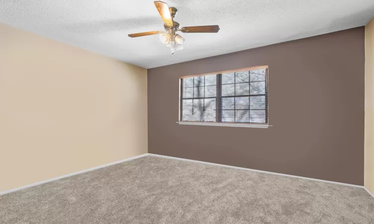 Spare room featuring ceiling fan, carpet floors, and a textured ceiling