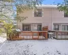 Snow covered rear of property with central AC and a wooden deck