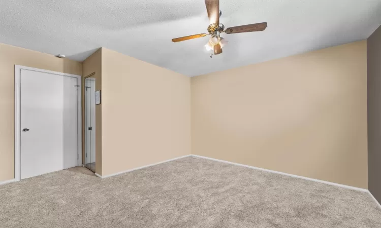 Unfurnished bedroom with a textured ceiling, light colored carpet, and ceiling fan