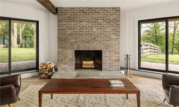 Living room with light wood-type flooring, a brick fireplace, and plenty of natural light