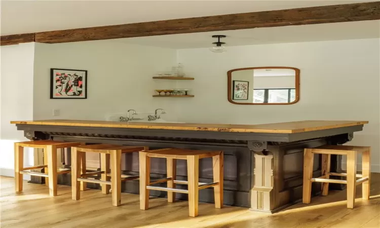 Bar featuring beam ceiling and light hardwood / wood-style flooring