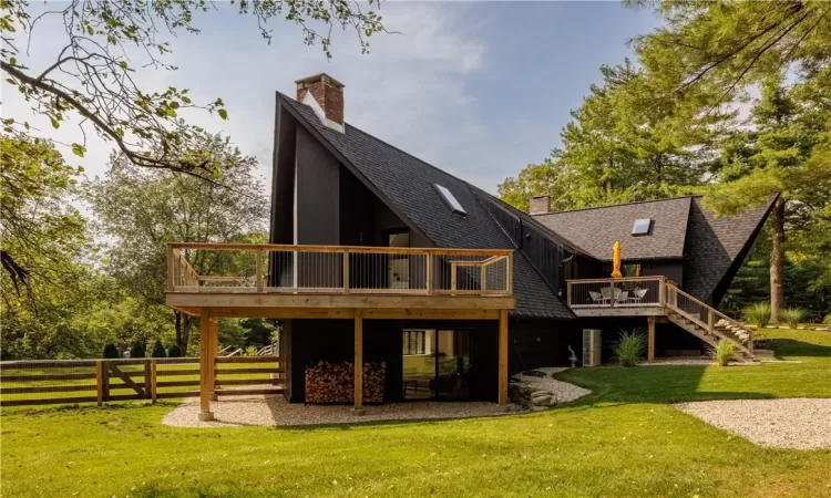 Rear view of house featuring a lawn and a deck