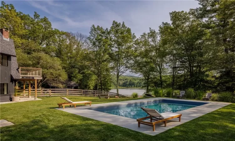 View of pool featuring a deck with water view, a lawn, and a patio