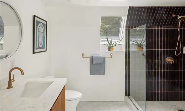 Bathroom with toilet, vanity, and tiled shower