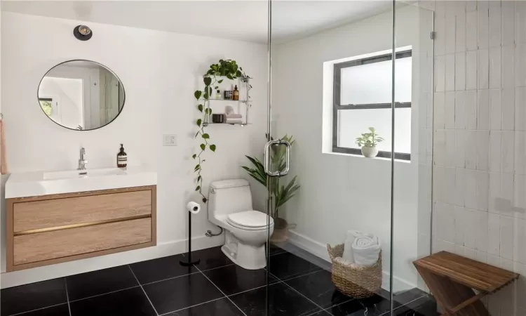 Bathroom with vanity, walk in shower, tile patterned floors, and toilet