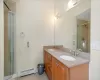 Bathroom featuring vanity, tile patterned flooring, baseboard heating, and a shower with door