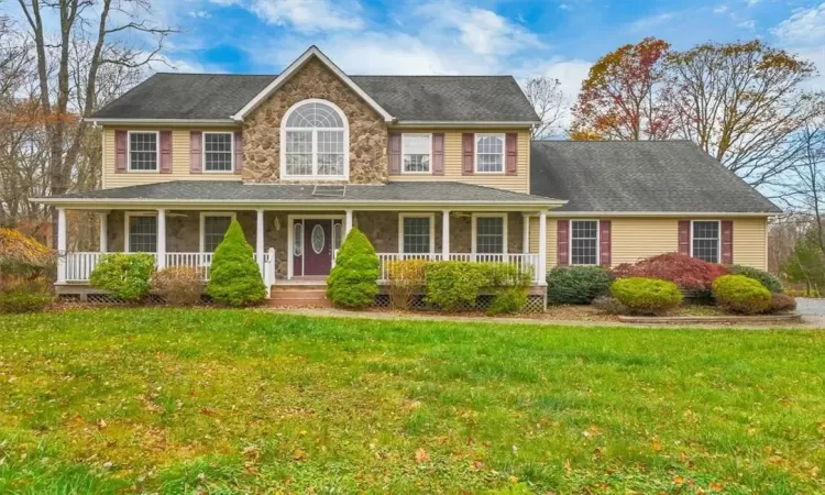 Colonial inspired home featuring a porch and a front lawn