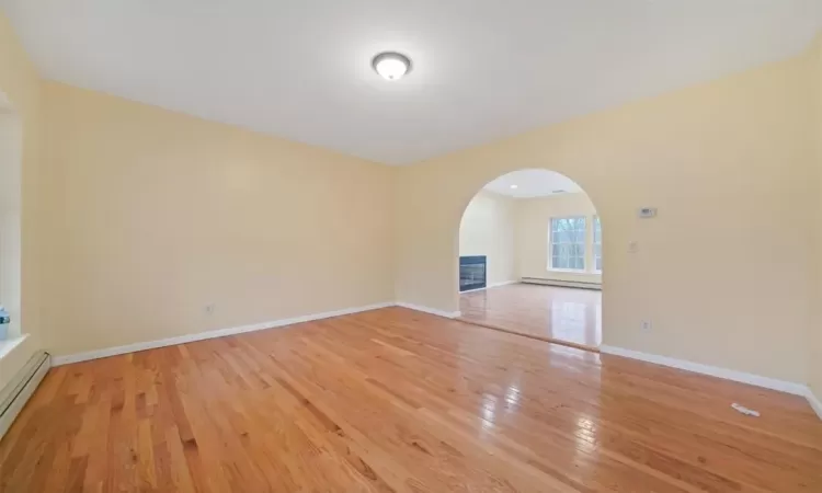 Unfurnished living room featuring a baseboard radiator and light hardwood / wood-style floors