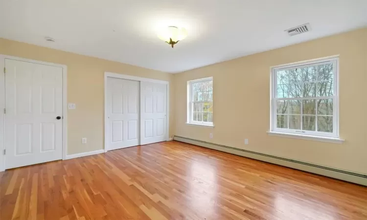 Unfurnished bedroom with light hardwood / wood-style floors and a baseboard radiator