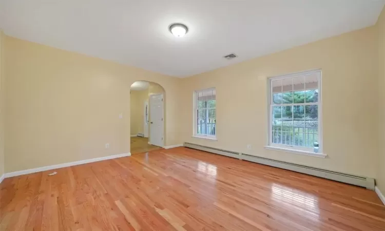 Unfurnished room with light hardwood / wood-style flooring, a healthy amount of sunlight, and a baseboard radiator