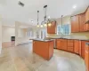 Kitchen with a kitchen island with sink, sink, a baseboard heating unit, and decorative light fixtures