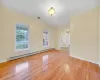 Unfurnished room featuring a baseboard heating unit, a chandelier, light wood-type flooring, and a wealth of natural light