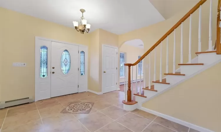 Tiled entrance foyer with a baseboard heating unit and a chandelier