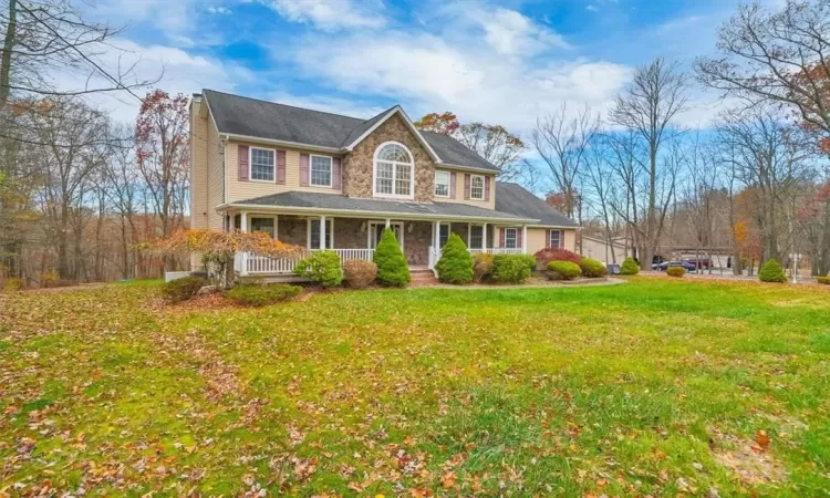 Colonial inspired home with a front yard and covered porch