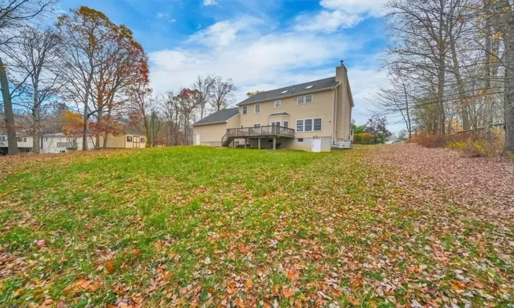 Back of house with a wooden deck and a yard