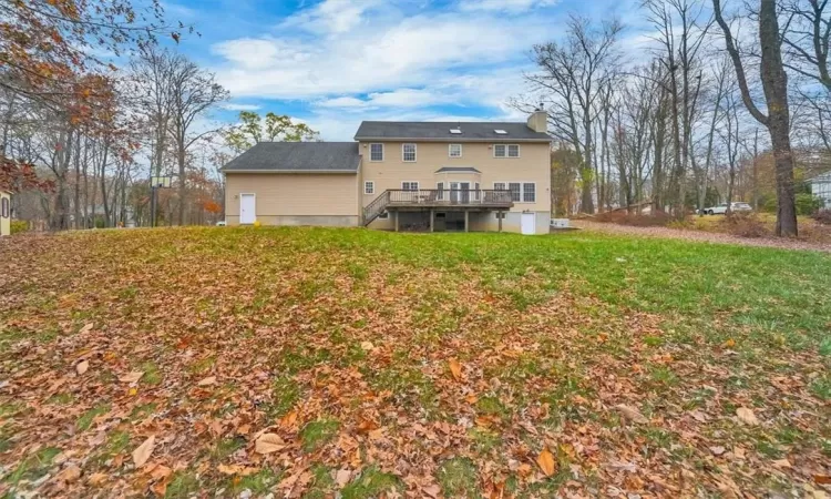 Back of house with a wooden deck and a yard