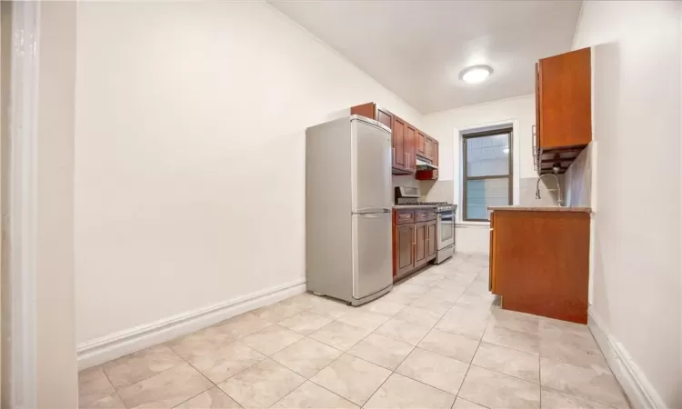 Kitchen featuring stainless steel appliances, light tile patterned flooring, extractor fan, and sink