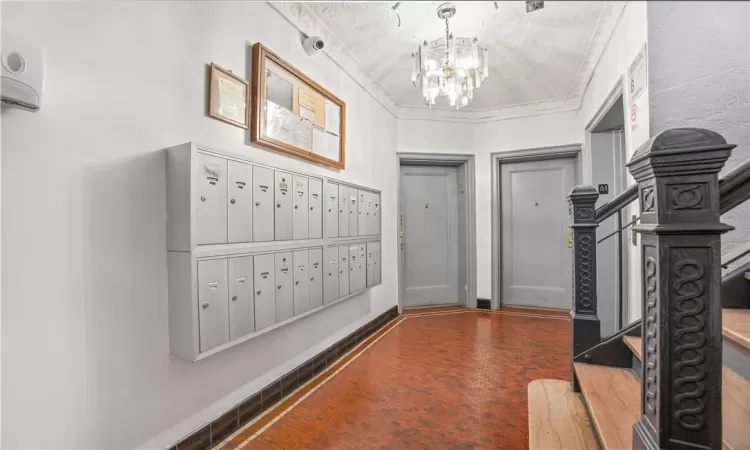 Foyer with a mail area, a chandelier, a textured ceiling, and crown molding