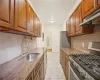 Kitchen with stainless steel appliances, sink, tasteful backsplash, dark stone counters, and ventilation hood