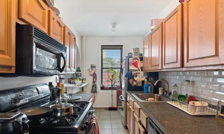 Kitchen with black appliances, tasteful backsplash, sink, and light tile patterned flooring